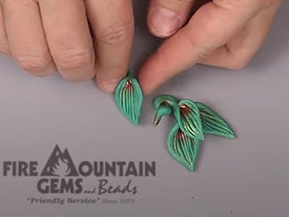 Hands forming green leaves in polymer clay